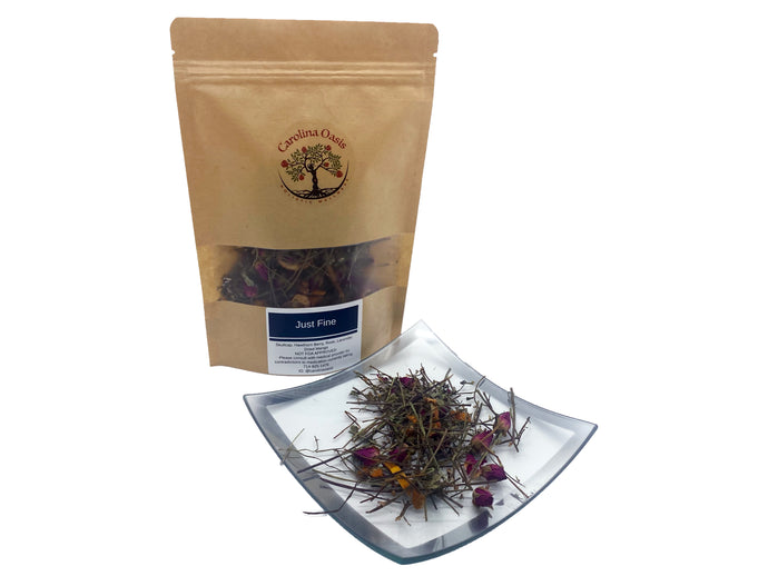Sealed, brown bag of Just Fine Stress and Anxiety reducing tea. The bag features the Carolina Oasis logo and a clear section of the bag allows you to see its herbal contents. In front of the bag is a small clear plate that contains a sampling of the tea/assortment of herbal ingredients.