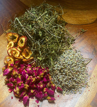 Load image into Gallery viewer, A wood bowl that contains a sampling of the tea/assortment of herbal ingredients found in the Just Fine tea.
